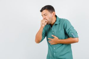 Young man suffering from cough in shirt and looking ill. front view.